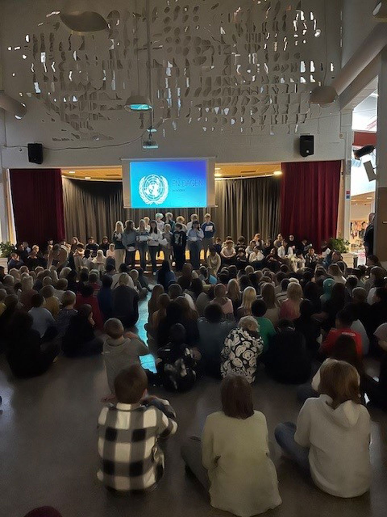 en gruppe mennesker som sitter i et rom med en stor skjerm