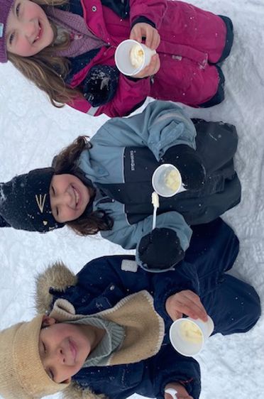 En gruppe barn som sitter i snøen og holder kaffekopper