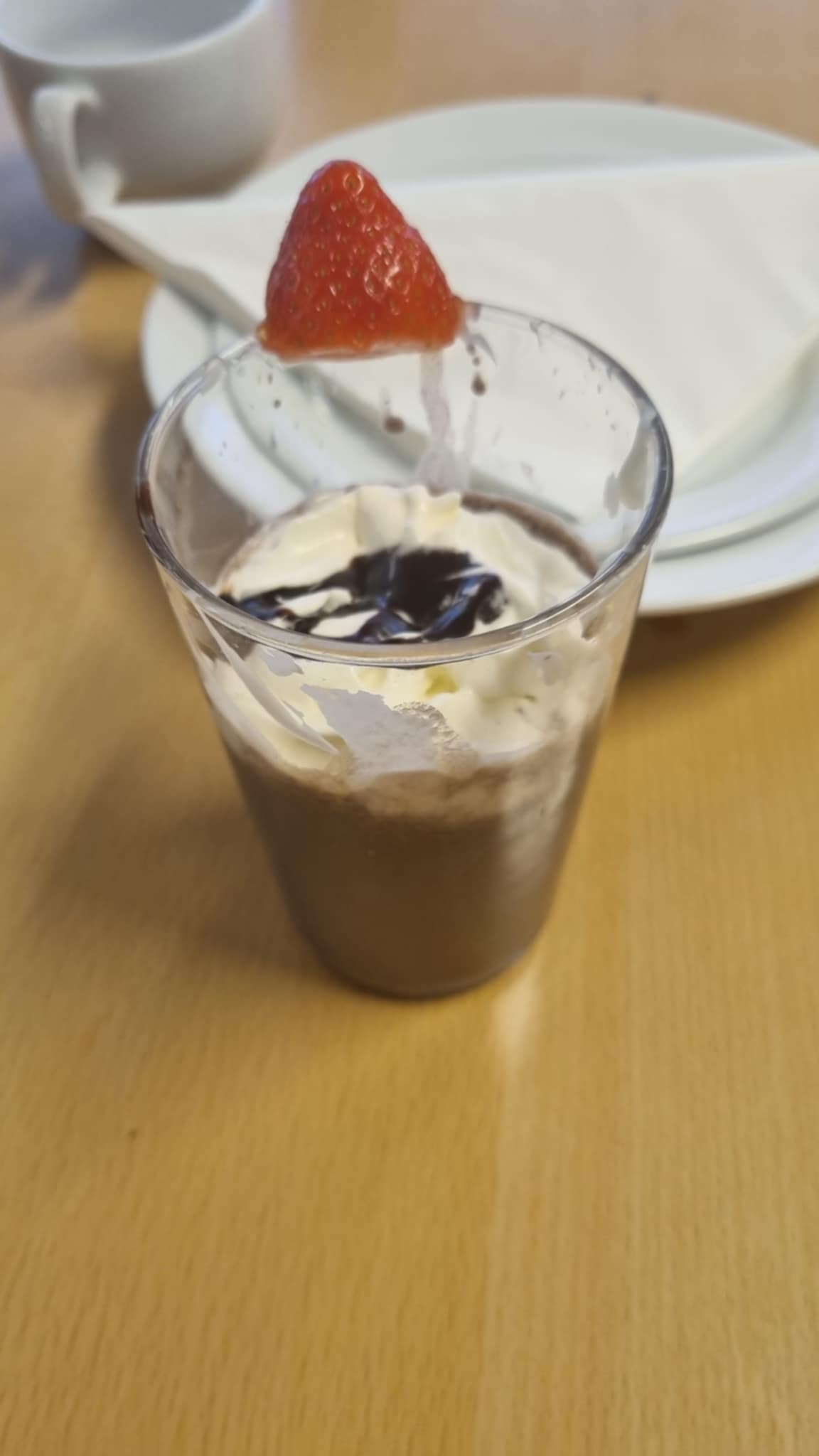 et glass melk med et jordbær på toppen